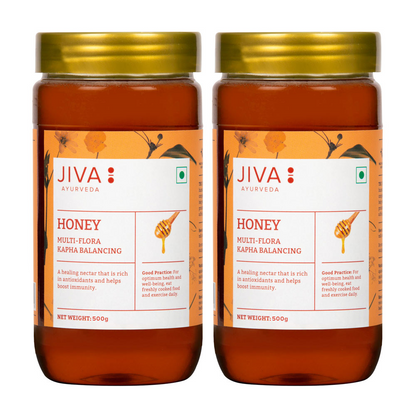 Jiva Ayurveda honey jar with golden honey spread, natural and pure, in a clear glass container.