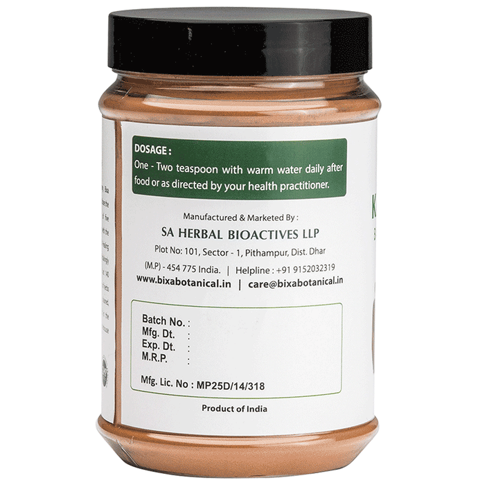 Bixa Botanical Kaiphal Powder in a clear glass jar, showing fine light brown Ayurvedic powder with a wooden spoon.
