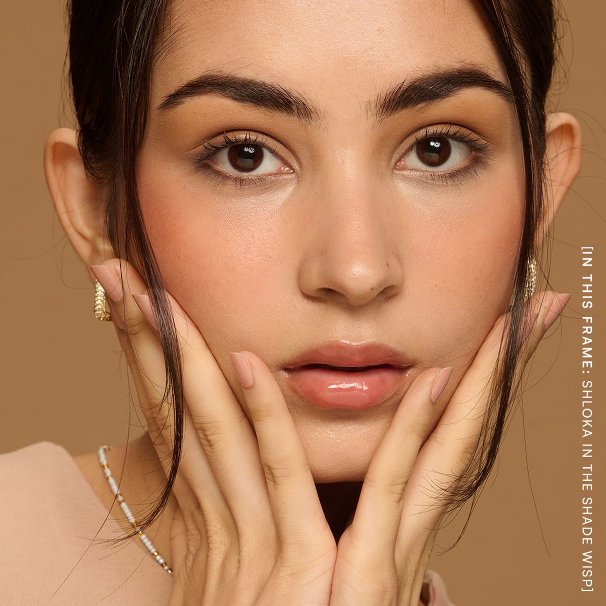 Gush Beauty Balmy Glossy Tinted Lip Oil in Soft Peach, showing a clear tube with peach-colored lip gloss inside.