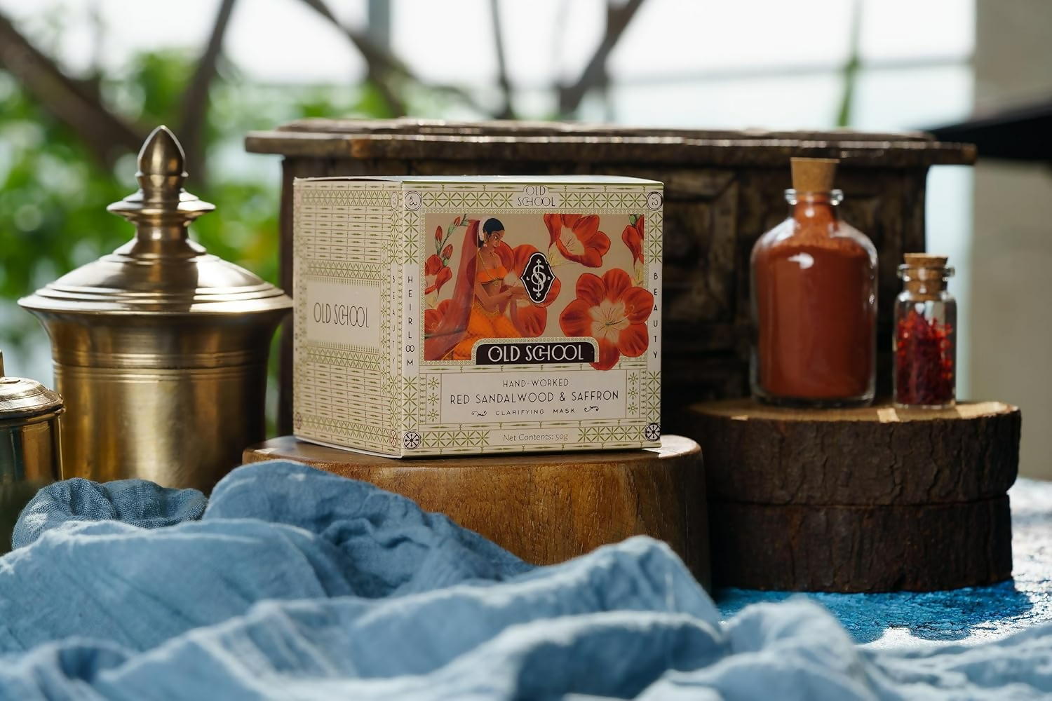 Old School Rituals red sandalwood and saffron face mask in a natural clay jar with a wooden spatula and fresh ingredients visible.