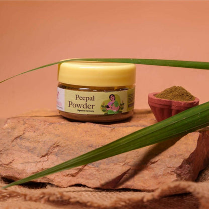 Nuskha Peepal Pepper Powder in a clear glass jar with a spoon, showing fine, reddish-brown pepper powder for culinary use.