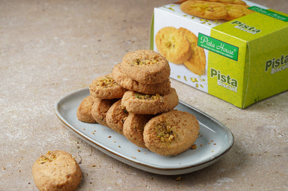Golden Pista House Pista Biscuits arranged on a plate, showcasing their crunchy texture and rich pistachio flavor.
