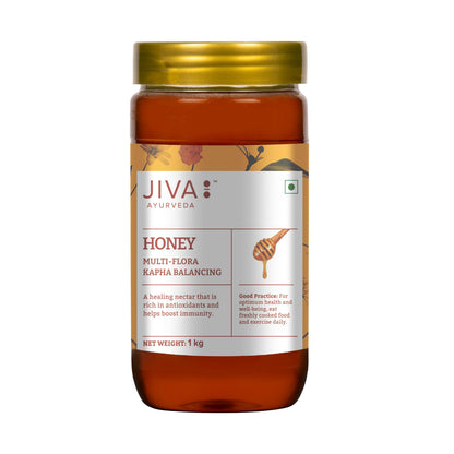 Jiva Ayurveda honey 1kg jar with golden, viscous honey filling the jar, showcasing natural sweet spread in a clear glass jar.