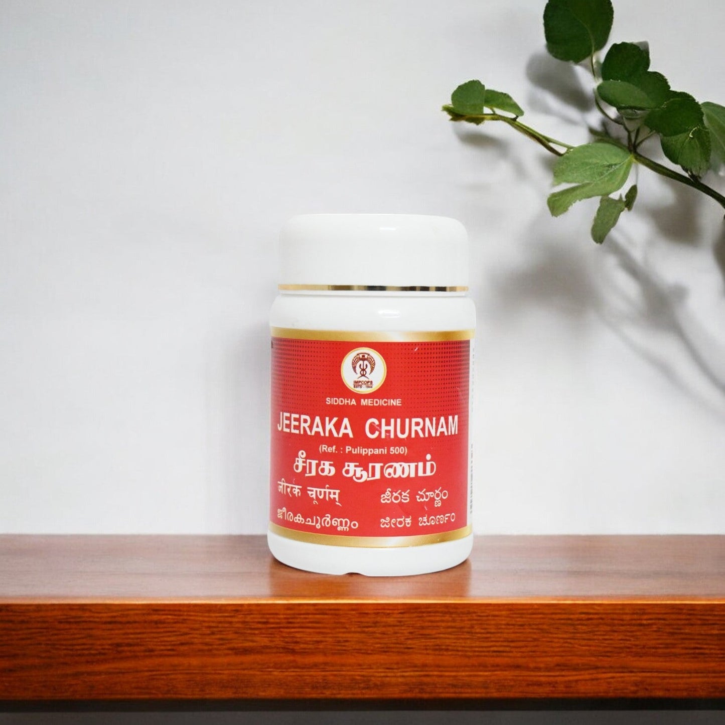 Impcops Jeeraka Churnam Ayurvedic herbal powder in a glass bowl with fresh cumin seeds on a white background.