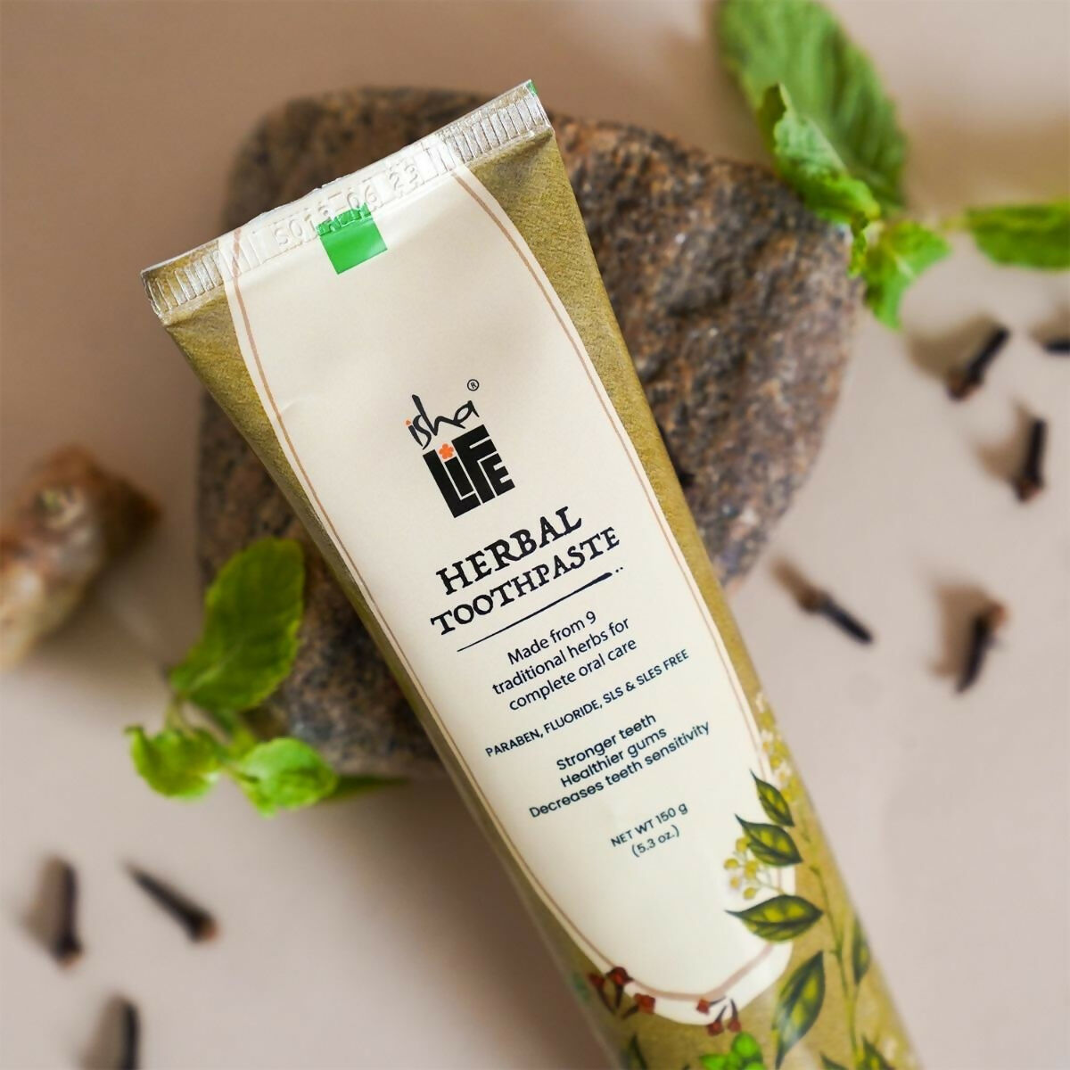 Isha Life herbal tooth powder and toothpaste combo in a natural, eco-friendly packaging on a wooden surface.