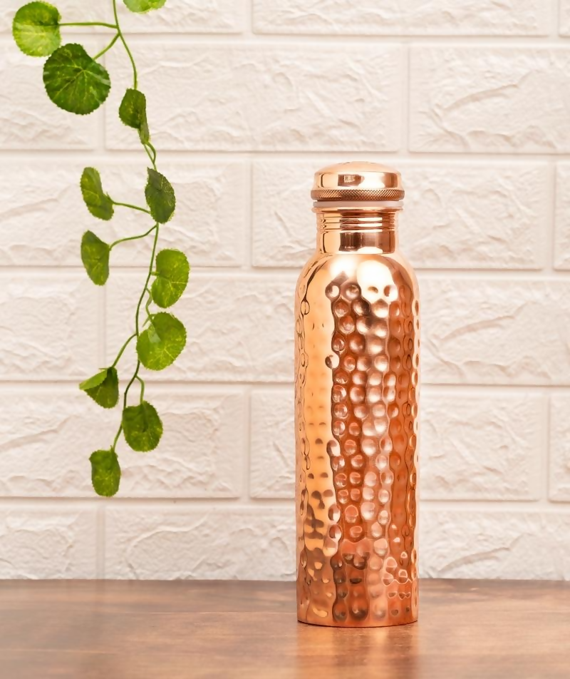 Hammered copper water bottle by Isha Life, 950 ml capacity with a textured finish, designed for storing and drinking water.