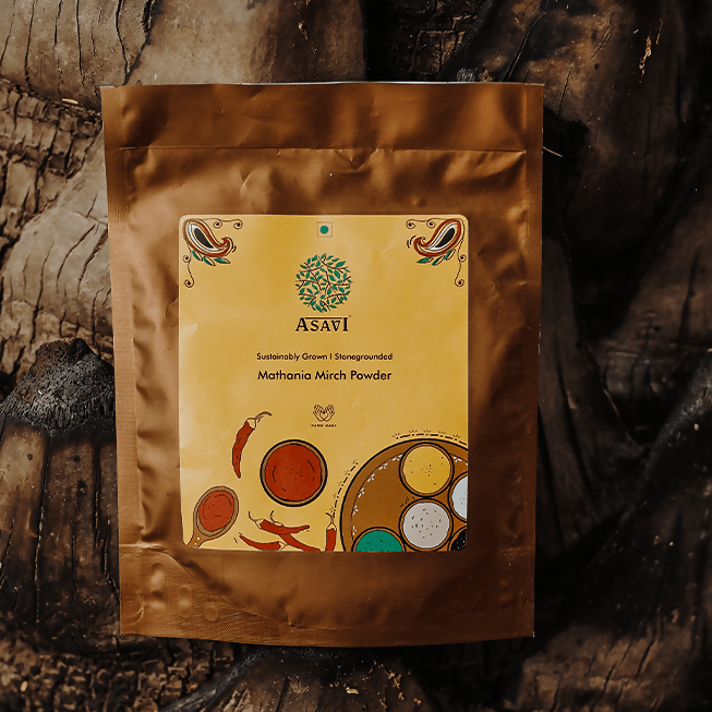 Asavi Stone Grounded Mathania Chilli Powder in a glass jar showing vibrant red chili flakes and fine powder.