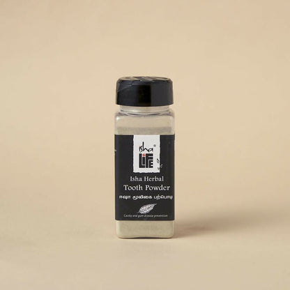 Isha Life herbal tooth powder and toothpaste combo in a natural packaging with herbal ingredients visible.