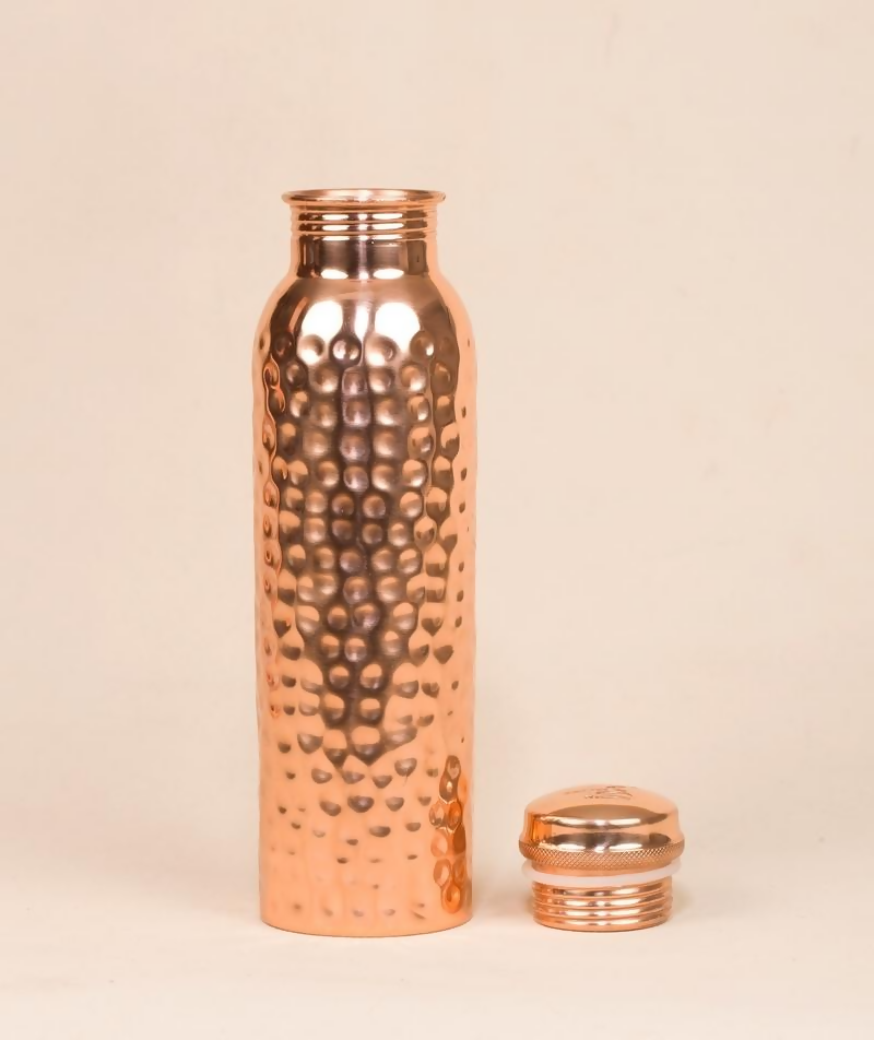 Hammered copper water bottle by Isha Life, 950 ml, showing its textured surface and sleek design for drinking water.
