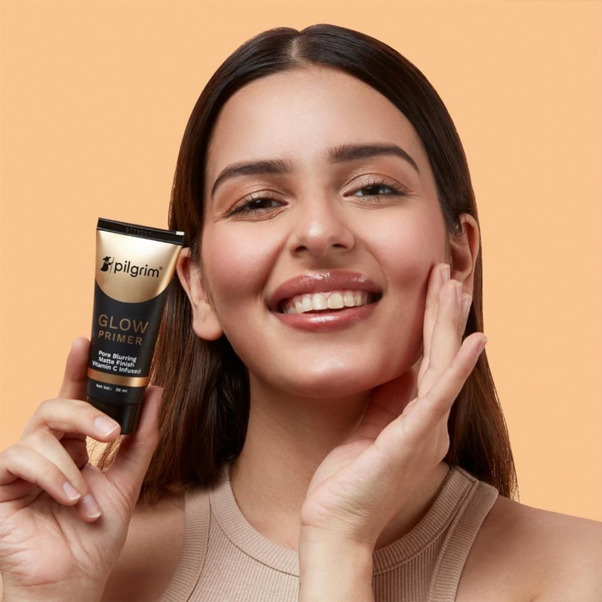 Pilgrim Instant Glow Primer with gold shimmer in a sleek tube, highlighting radiant, luminous skin for a natural glow.