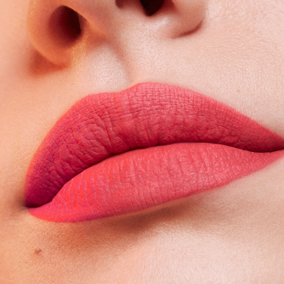 Estee Lauder Pure Color Whipped Matte Lip Color in Hot Fuse, showing vibrant coral-orange lipstick in a sleek tube.