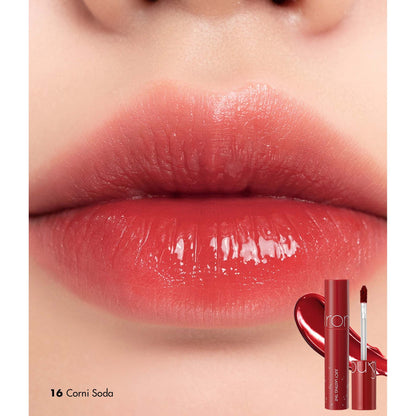 Rom&nd The Juicy Lasting Tint in 16 Corni Soda, showing vibrant orange-red lip tint in sleek packaging.