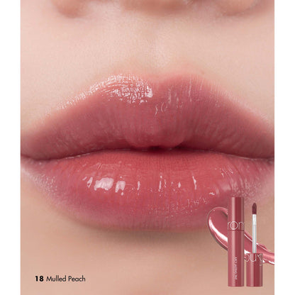 Rom&nd The Juicy Lasting Tint in 18 Mulled Peach, showcasing the peach-colored lip tint with a sleek tube and applicator.