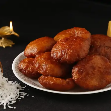 Gummadi Foods Kobbari Burelu, traditional North Indian coconut sweet, golden-brown deep-fried dessert on a plate.