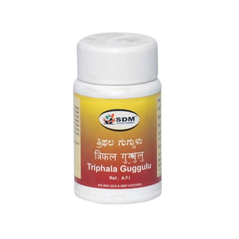 Sdm Ayurveda Triphala Guggulu Ayurvedic tablets in a bottle with tablets visible inside, natural herbal supplement for wellness.